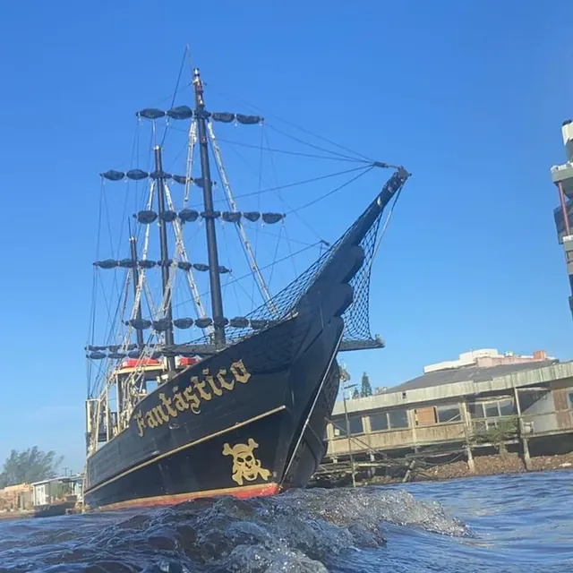 Navio pirata Fantástico navegando sob céu azul, visto do nível da água