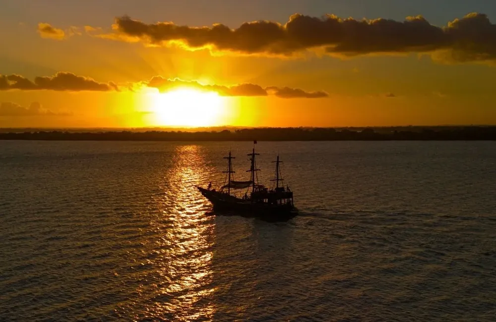 Barco pirata navegando no Guaíba ao pôr do sol, em Porto Alegre