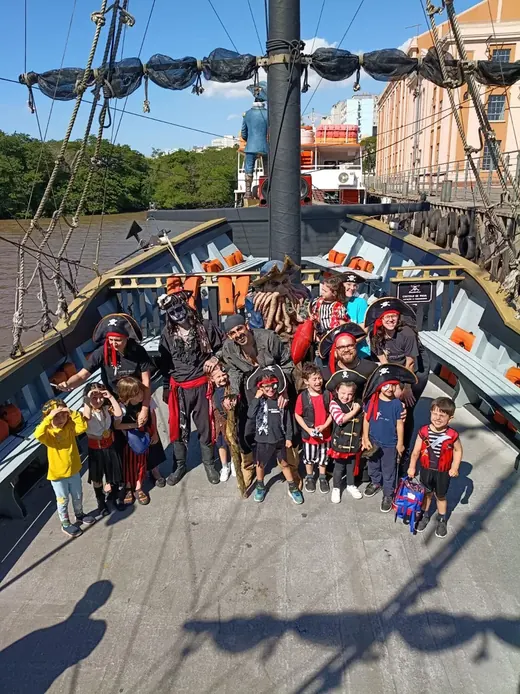 Crianças fantasiadas de pirata posando com a tripulação no convés do navio